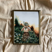 Load image into Gallery viewer, An oil painting in a gold frame laying on cream linen fabric. There is a girl holding a bouquet of flowers in front of her face. She is wearing a cream shirt and a brown skirt and is standing in a field of Queen Anne&#39;s lace flowers. There is an orange golden glow coming from behind the trees, it looks like gloaming hour.  
