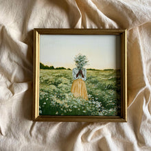 Load image into Gallery viewer, An oil painting in a gold frame laying on cream linen fabric. There is a distant row of trees with a slight golden glow coming from behind them. There is a daisy field with a black girl wearing a light blue shirt and a yellow skirt. She is holding a bouquet of flowers in front of her face. 
